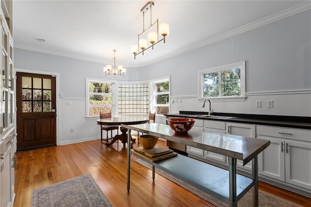 dining area with crown molding, plenty of natural light, light wood finished floors, and an inviting chandelier