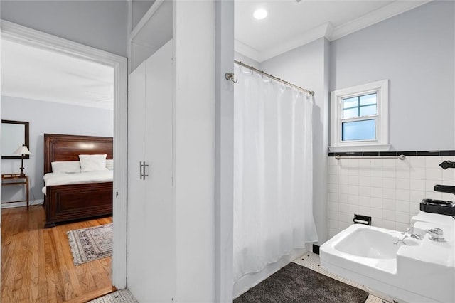 full bath featuring curtained shower, wood finished floors, tile walls, ornamental molding, and ensuite bath