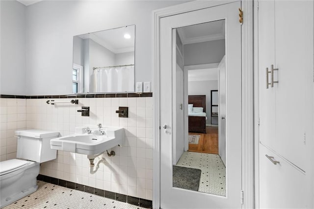 bathroom with crown molding, tile walls, toilet, a sink, and tile patterned flooring