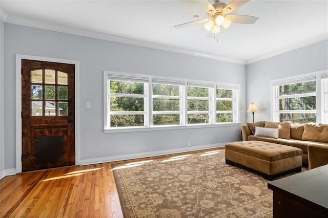 living room featuring baseboards, ceiling fan, wood finished floors, and crown molding