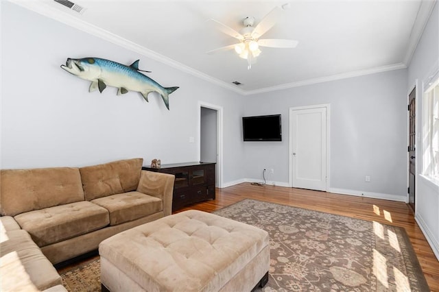 living area with a ceiling fan, crown molding, baseboards, and wood finished floors