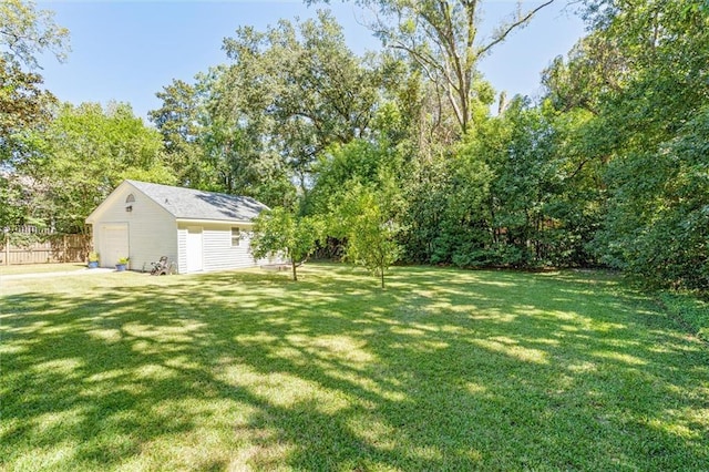 view of yard with an outbuilding, a detached garage, and fence