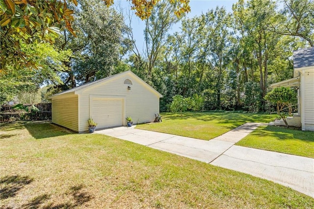 detached garage featuring concrete driveway and fence