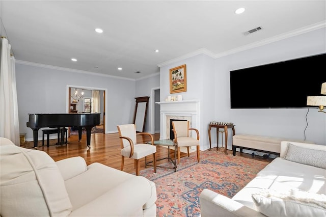 living area featuring visible vents, wood finished floors, crown molding, a fireplace, and recessed lighting