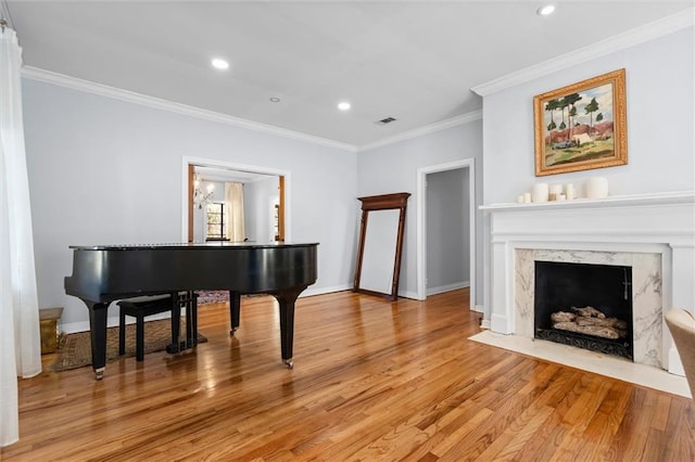 living area with light wood-style floors, baseboards, crown molding, and a high end fireplace