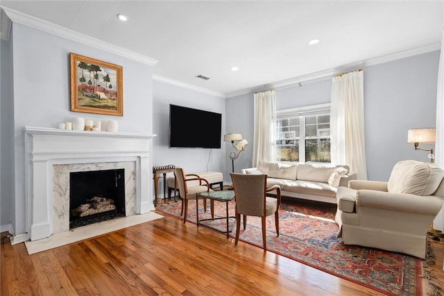 living room featuring crown molding, recessed lighting, visible vents, a high end fireplace, and wood finished floors