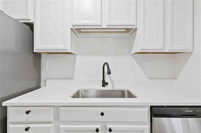 kitchen featuring stainless steel dishwasher, white cabinetry, and sink