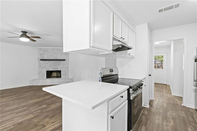 kitchen featuring white cabinetry, ceiling fan, stainless steel electric range oven, dark hardwood / wood-style floors, and a stone fireplace