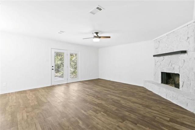 unfurnished living room featuring ceiling fan, dark hardwood / wood-style floors, and a stone fireplace