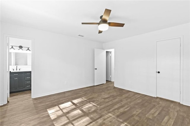 unfurnished bedroom with sink, ceiling fan, a closet, dark hardwood / wood-style floors, and ensuite bath