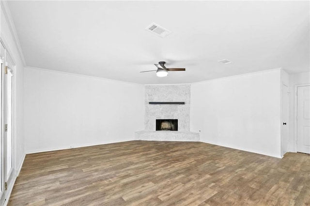 unfurnished living room featuring wood-type flooring, a fireplace, ceiling fan, and ornamental molding