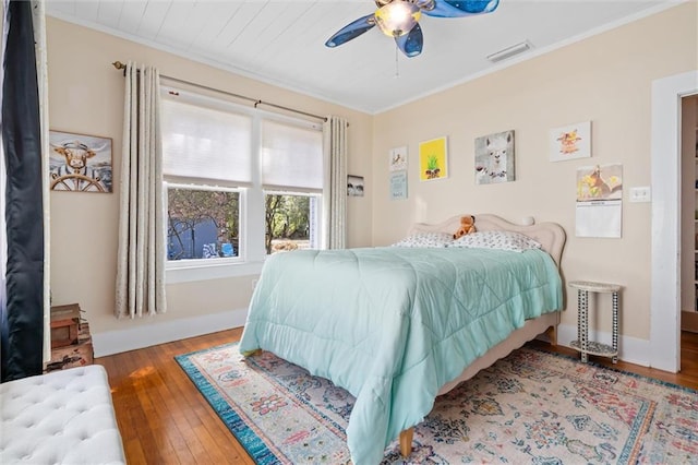 bedroom featuring hardwood / wood-style flooring, visible vents, and ornamental molding