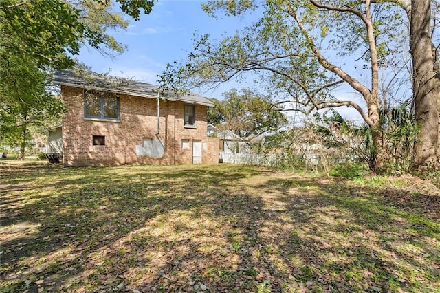 exterior space with brick siding, a lawn, and fence