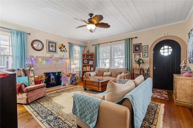 living room featuring a ceiling fan, wood finished floors, arched walkways, crown molding, and wood ceiling