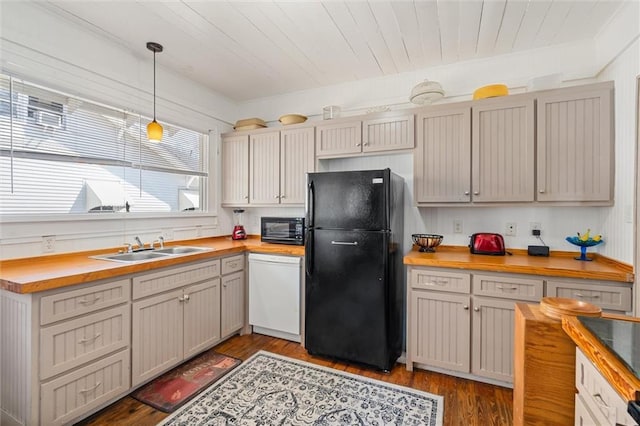 kitchen featuring dark wood finished floors, a sink, black appliances, pendant lighting, and wood counters