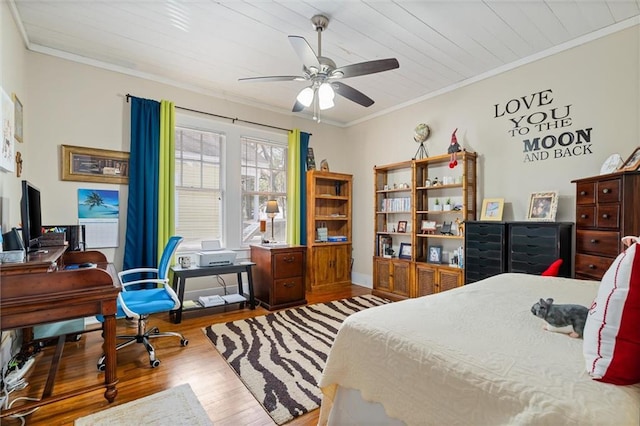 bedroom featuring crown molding, a ceiling fan, and wood finished floors