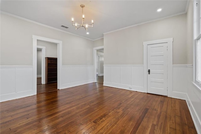 spare room with ornamental molding, dark wood-type flooring, and an inviting chandelier