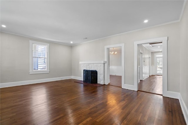 unfurnished living room with plenty of natural light, crown molding, a high end fireplace, and dark wood-type flooring