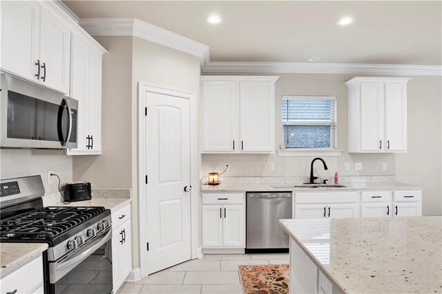 30768 Bauer Ave, Spanish Fort, AL 36527 - kitchen featuring stainless steel appliances, light stone counters, white cabinetry, light tile patterned floors, and ornamental molding