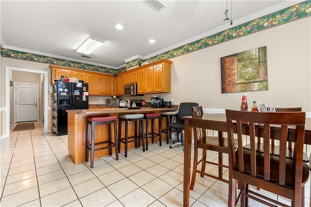 kitchen with kitchen peninsula, ornamental molding, a kitchen bar, black fridge with ice dispenser, and a textured ceiling