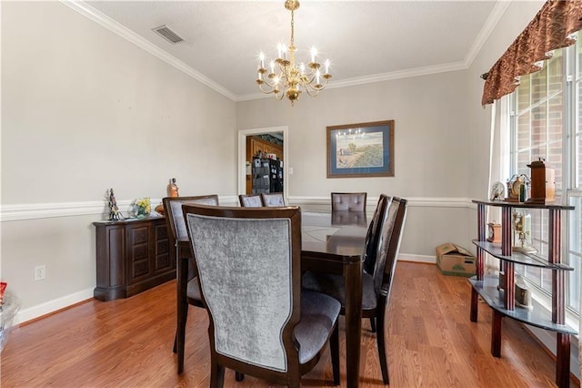 dining area with ornamental molding, a notable chandelier, and light wood-type flooring