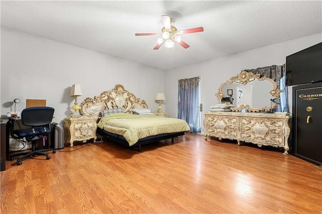 bedroom with a textured ceiling, hardwood / wood-style flooring, and ceiling fan