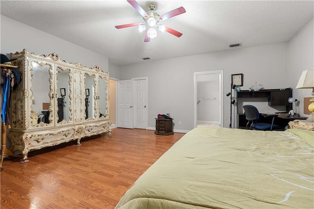 bedroom with hardwood / wood-style floors, a textured ceiling, and ceiling fan