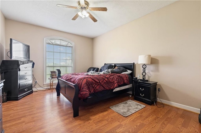 bedroom with ceiling fan, a textured ceiling, and light hardwood / wood-style flooring