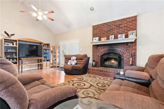 living room with hardwood / wood-style floors, ceiling fan, high vaulted ceiling, and a brick fireplace