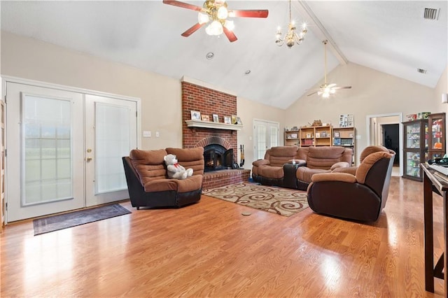 living room featuring light hardwood / wood-style floors, beam ceiling, ceiling fan with notable chandelier, a brick fireplace, and high vaulted ceiling