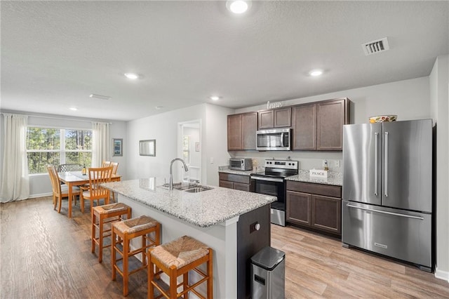 10232 Brodick Loop, Spanish Fort, AL 36527 - kitchen featuring appliances with stainless steel finishes, a sink, light wood-type flooring, a breakfast bar area, and an island with sink