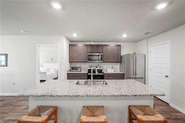 10232 Brodick Loop, Spanish Fort, AL 36527 - kitchen with appliances with stainless steel finishes, a sink, a kitchen breakfast bar, dark brown cabinets, and baseboards