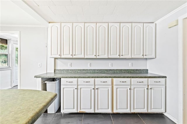 kitchen featuring crown molding, white cabinetry, and dark tile patterned flooring