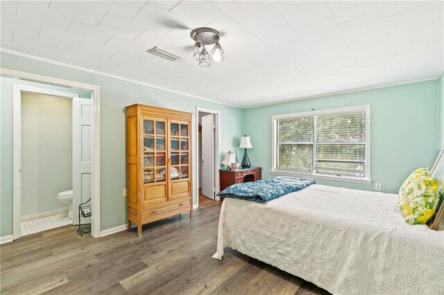 bedroom with ornamental molding, hardwood / wood-style floors, and ensuite bath