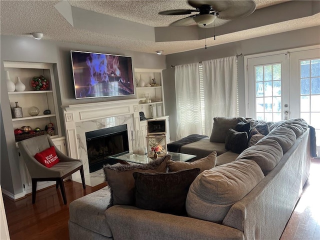 living room featuring a high end fireplace, french doors, a textured ceiling, ceiling fan, and wood-type flooring