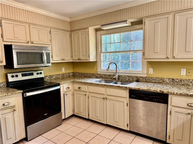 kitchen with light tile patterned floors, ornamental molding, stainless steel appliances, and a sink