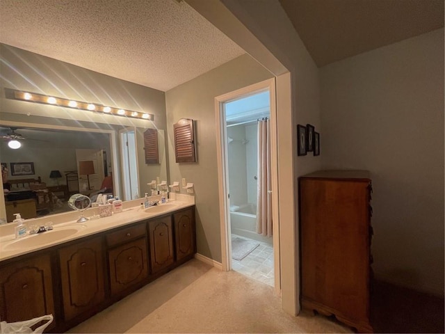 full bathroom with a sink, a textured ceiling, baseboards, and double vanity