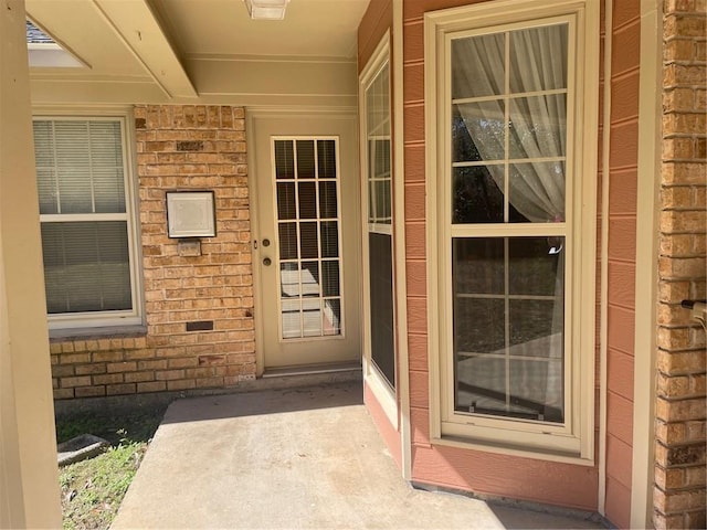 property entrance with a porch and brick siding