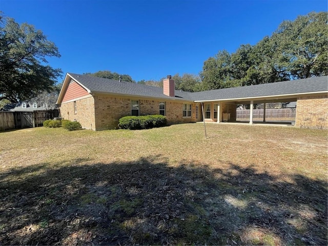 back of property featuring a yard, brick siding, a chimney, and fence