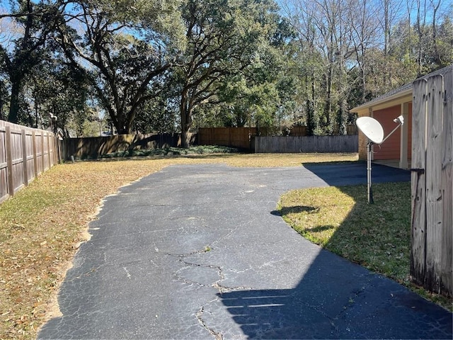 view of yard featuring aphalt driveway and a fenced backyard