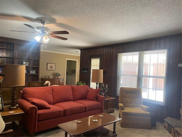 living room featuring carpet, crown molding, a ceiling fan, and a textured ceiling