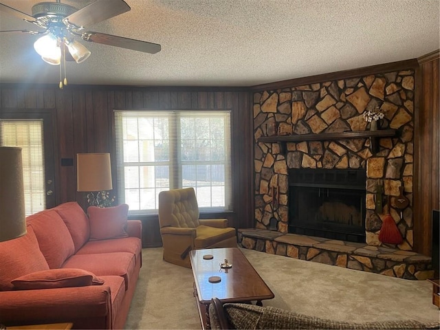 living room featuring a textured ceiling, a stone fireplace, carpet flooring, and wooden walls