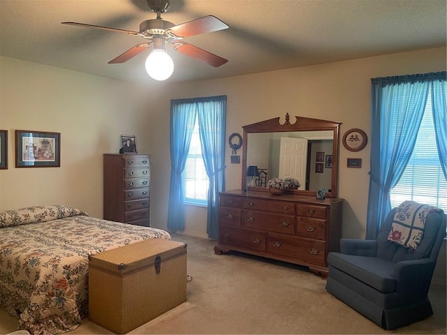 bedroom featuring a ceiling fan, light carpet, and a textured ceiling