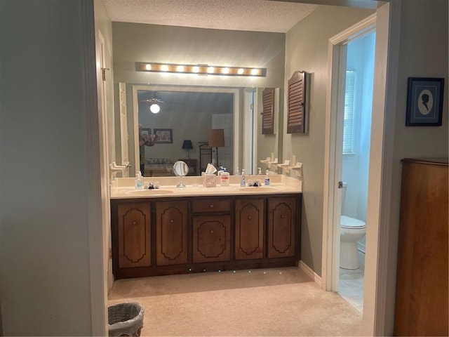 ensuite bathroom with double vanity, a textured ceiling, and a sink