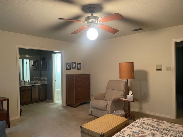 bedroom featuring light carpet, baseboards, visible vents, connected bathroom, and a textured ceiling