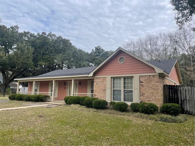 single story home featuring brick siding, a porch, a front yard, and fence