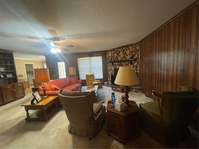 living room featuring a textured ceiling, wooden walls, light carpet, a fireplace, and a ceiling fan