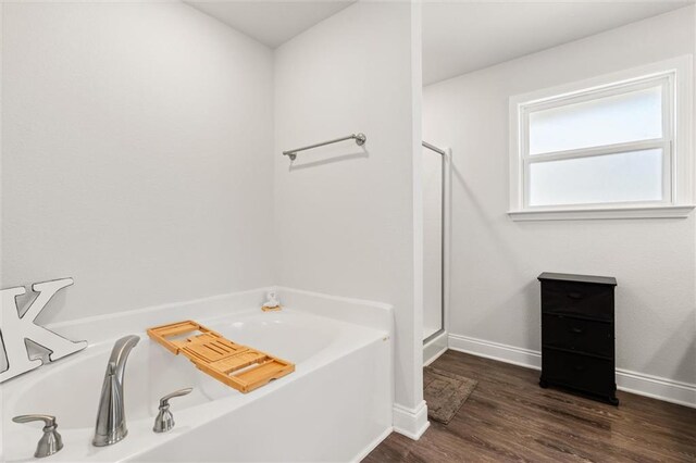 bathroom with a garden tub, wood finished floors, baseboards, and a stall shower