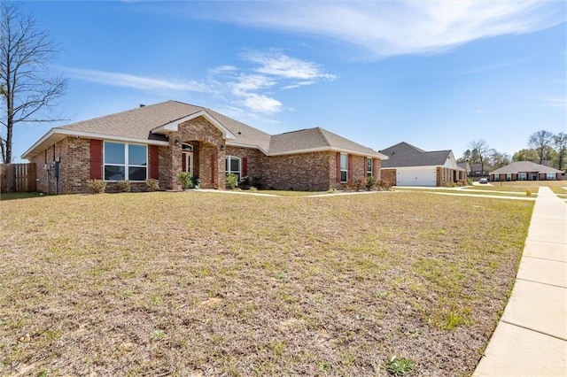 single story home featuring a front lawn, fence, and brick siding