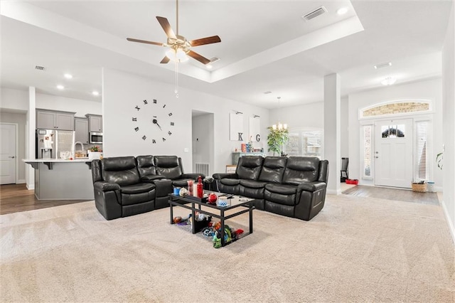 carpeted living area featuring visible vents, recessed lighting, and a raised ceiling